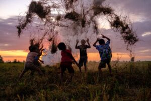 Bambini giocano in un campo al tramonto, in controluce